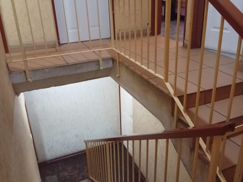 A functional interior staircase and landing area featuring tiled flooring and metal balustrades with wooden handrails, providing access between levels.