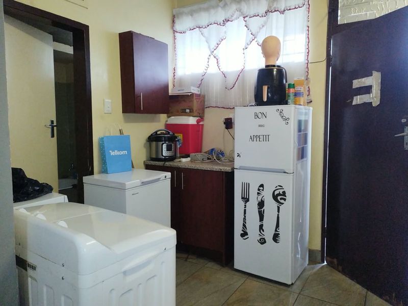 A compact kitchen area featuring built-in cabinetry, laminate countertops, and tiled flooring, requiring cosmetic updates to improve its overall aesthetic and functionality.
