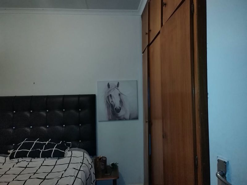 A bedroom featuring built-in wooden cupboards and standard ceiling cornicing, providing functional storage space within the room.