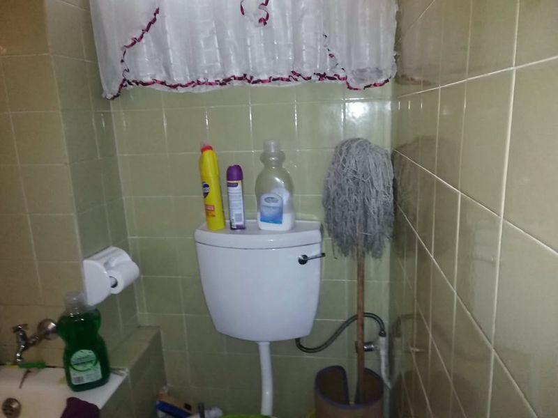 A compact bathroom featuring dated ceramic wall tiling and standard toilet fixtures, requiring modernization to improve aesthetic appeal.