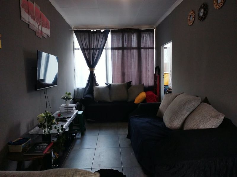 A living room featuring tiled flooring and a large window, providing natural light to the space.