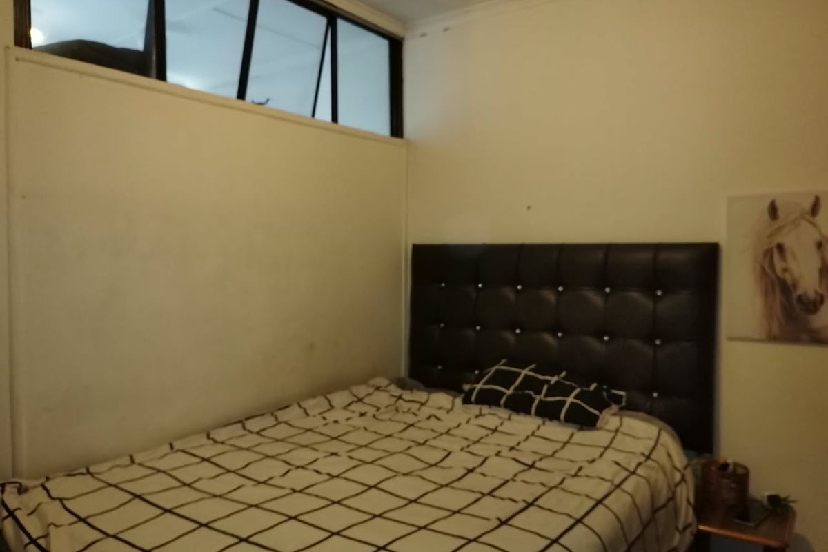 A bedroom featuring a high-level clerestory window providing natural light, with neutral wall finishes.