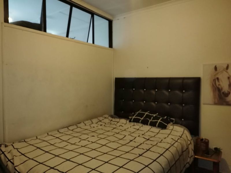 A bedroom featuring a high-level clerestory window providing natural light, with neutral wall finishes.