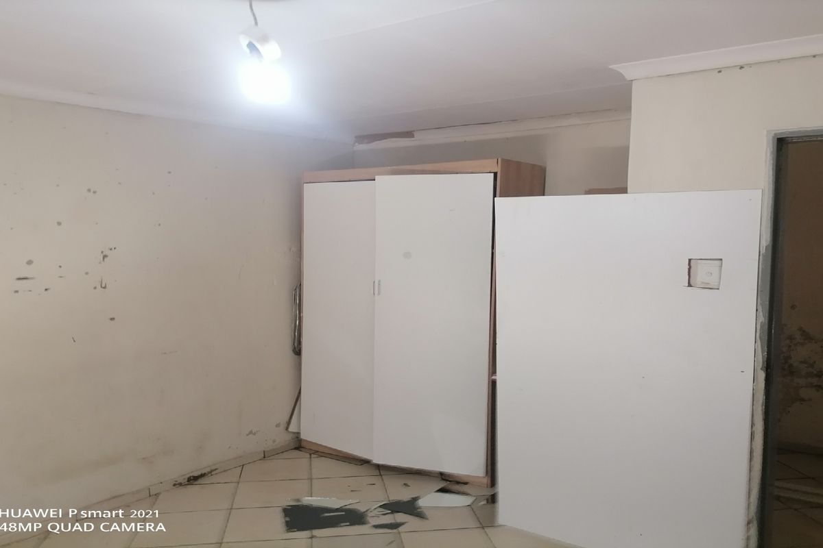 A bedroom space featuring tiled flooring and a built-in wardrobe, currently requiring significant cosmetic repairs and wall maintenance.