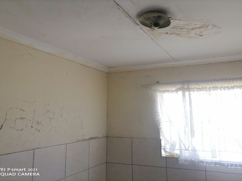 A bathroom interior showing significant wall cracking and ceiling water damage, requiring maintenance and cosmetic renovation to restore the space.