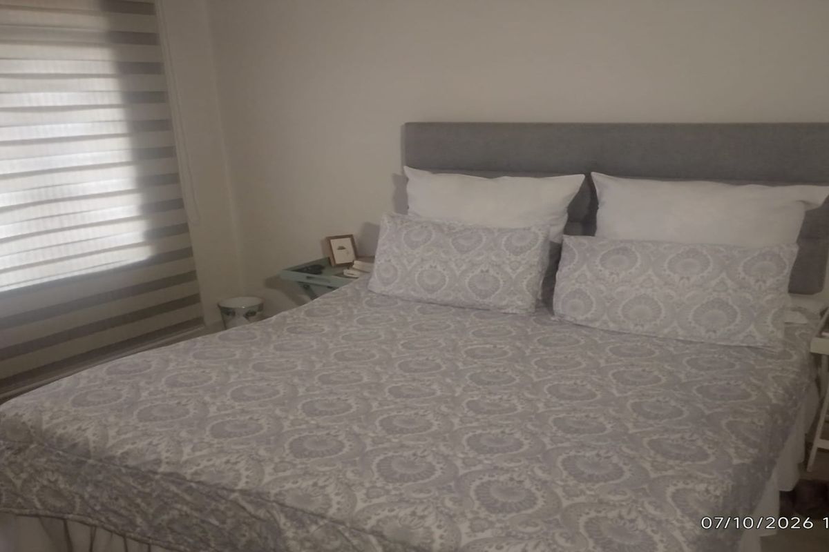 A bedroom featuring neutral walls and modern roller blinds, providing a clean and functional space.
