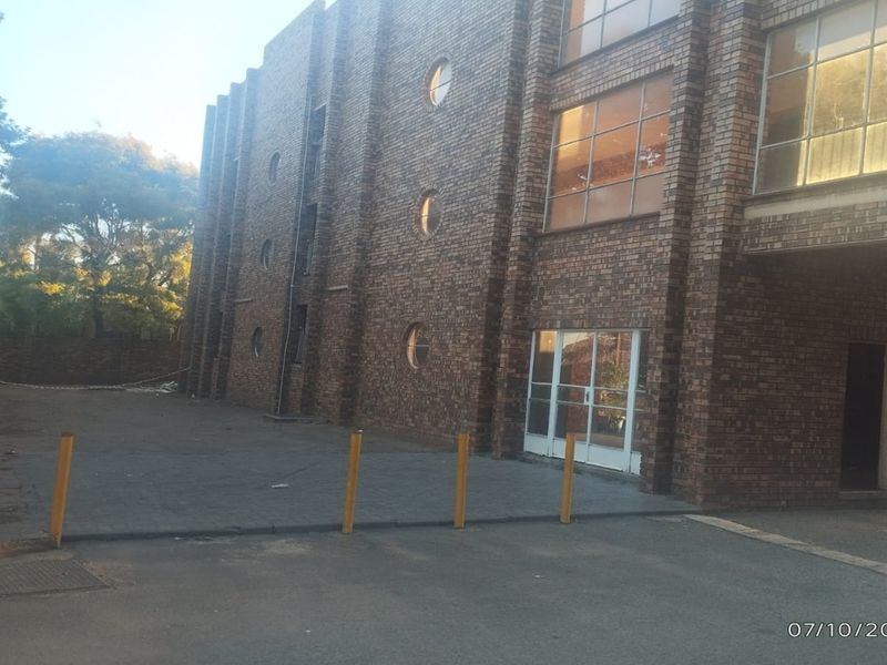 Exterior view of a multi-story face brick apartment building featuring circular and rectangular windows with an adjacent paved driveway area.