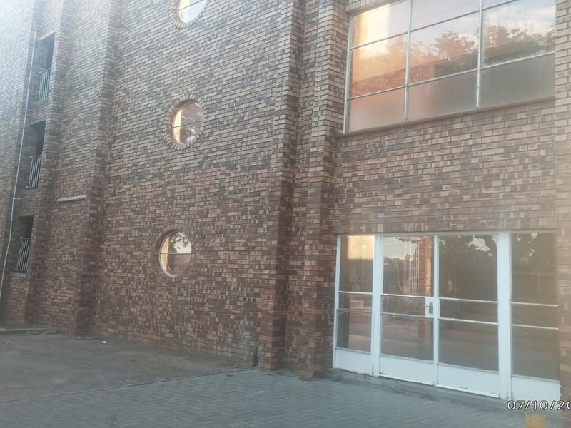 Exterior view of an apartment building featuring a face brick facade, circular windows, and a glass panel entrance.