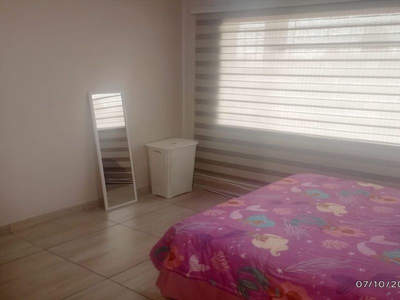 A bedroom featuring tiled flooring and modern zebra blinds, providing a neutral base for personalization.