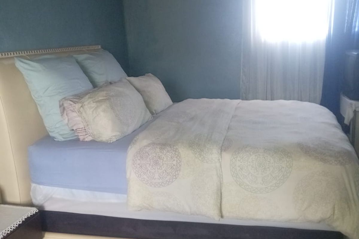 A bedroom featuring exposed timber ceiling beams and blue painted walls, currently requiring finishing work to the ceiling and wall surfaces.
