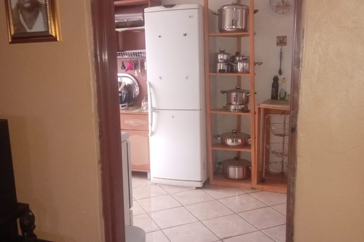 A view into a functional kitchen featuring tiled flooring and built-in cabinetry, currently showing signs of wear and requiring cosmetic updates.