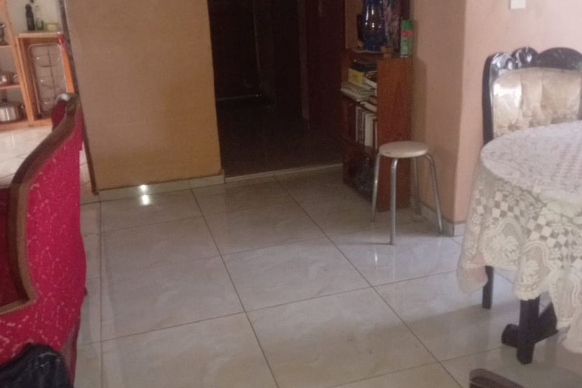 A living area featuring tiled flooring and access to internal hallways and adjacent rooms.