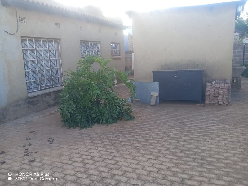 Rear exterior courtyard featuring paved flooring and masonry walls with security-barred windows.