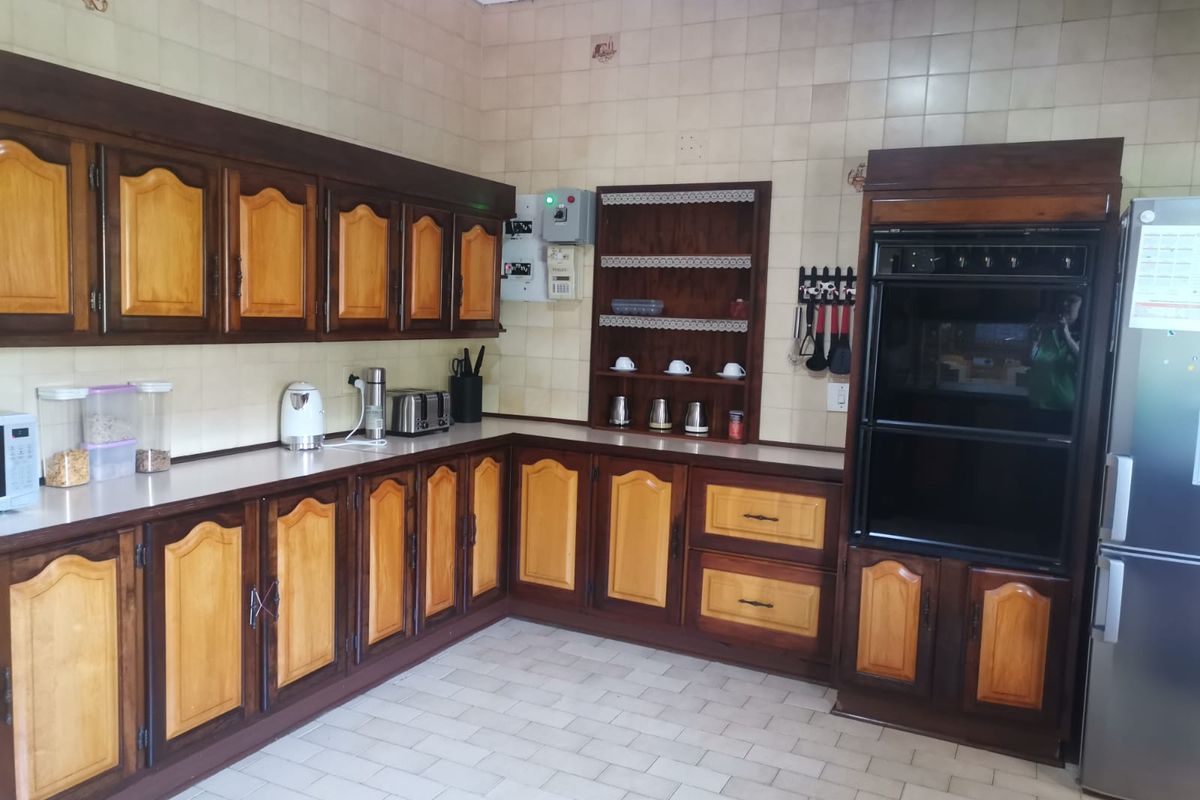 A functional kitchen featuring traditional wooden cabinetry, built-in double oven, tiled splashbacks, and tiled flooring, offering a classic layout with ample storage space.