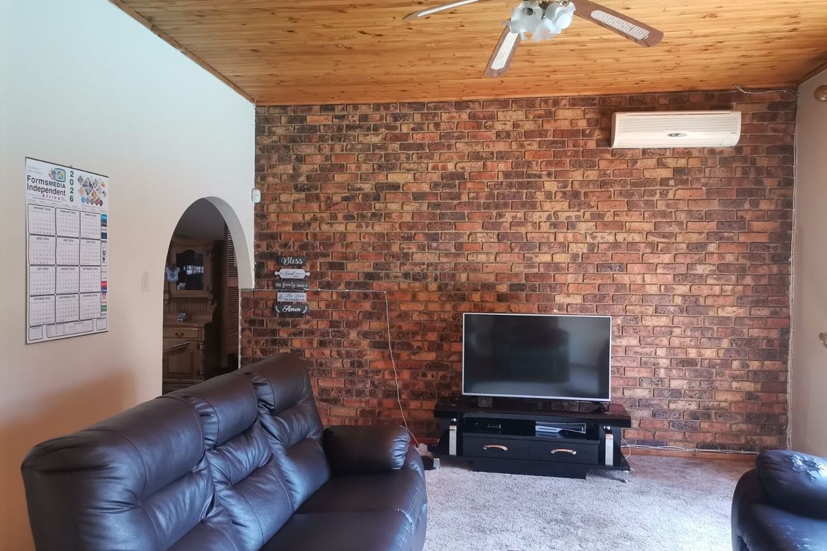 Living room featuring a prominent exposed brick wall, timber ceiling, ceiling fan, and split-system air conditioning unit.