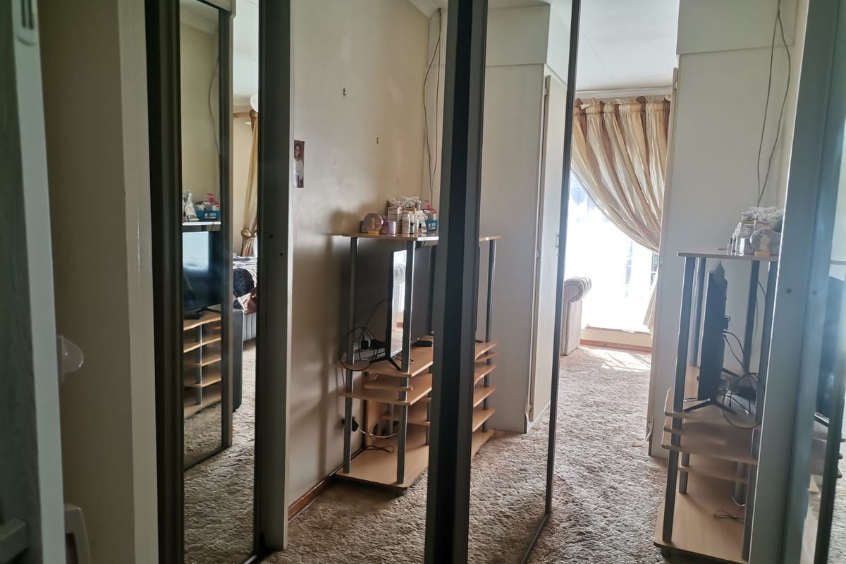 Bedroom featuring mirrored sliding wardrobe doors and carpet flooring, offering potential for cosmetic updates to enhance the living space.