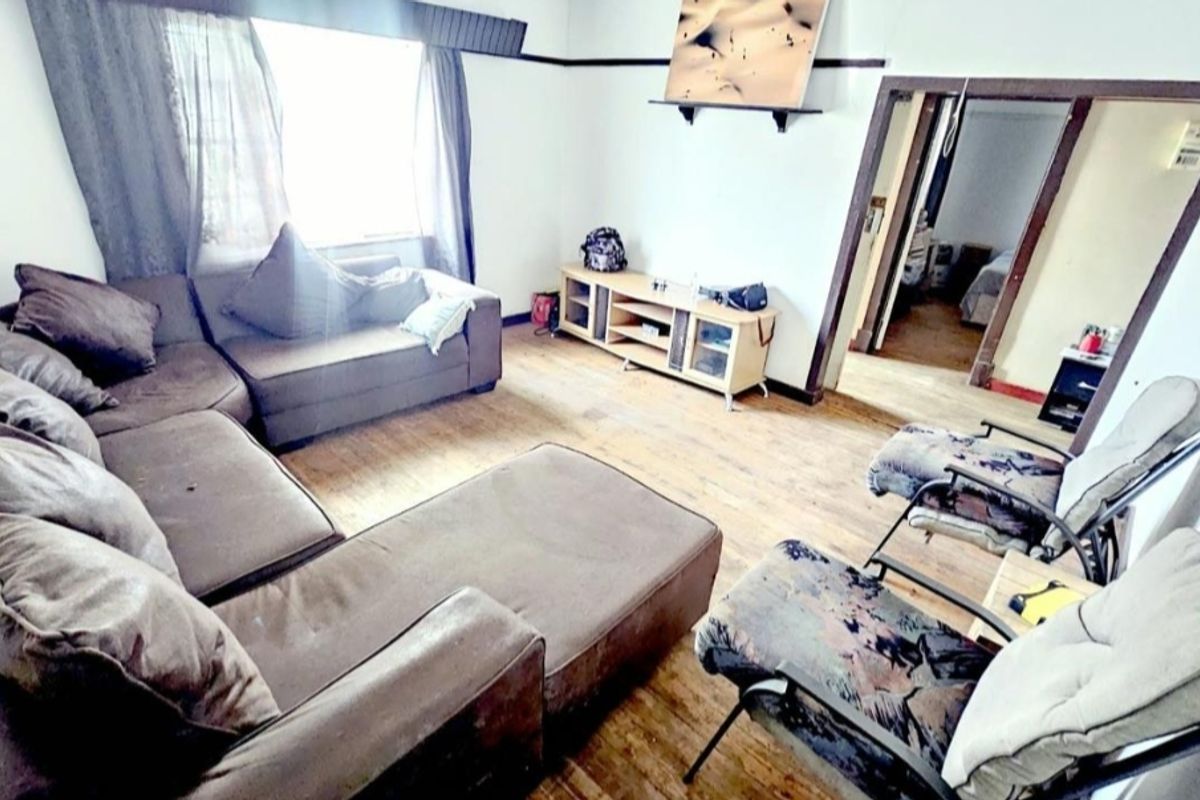 A living room featuring timber flooring and a picture rail, requiring cosmetic updates to improve the overall condition and aesthetic appeal.