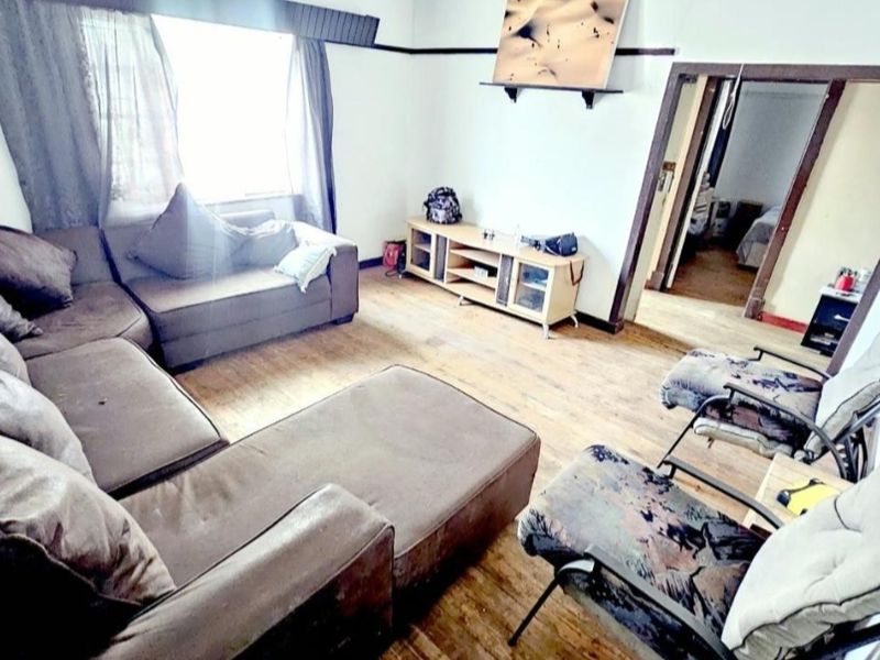 A living room featuring timber flooring and a picture rail, requiring cosmetic updates to improve the overall condition and aesthetic appeal.