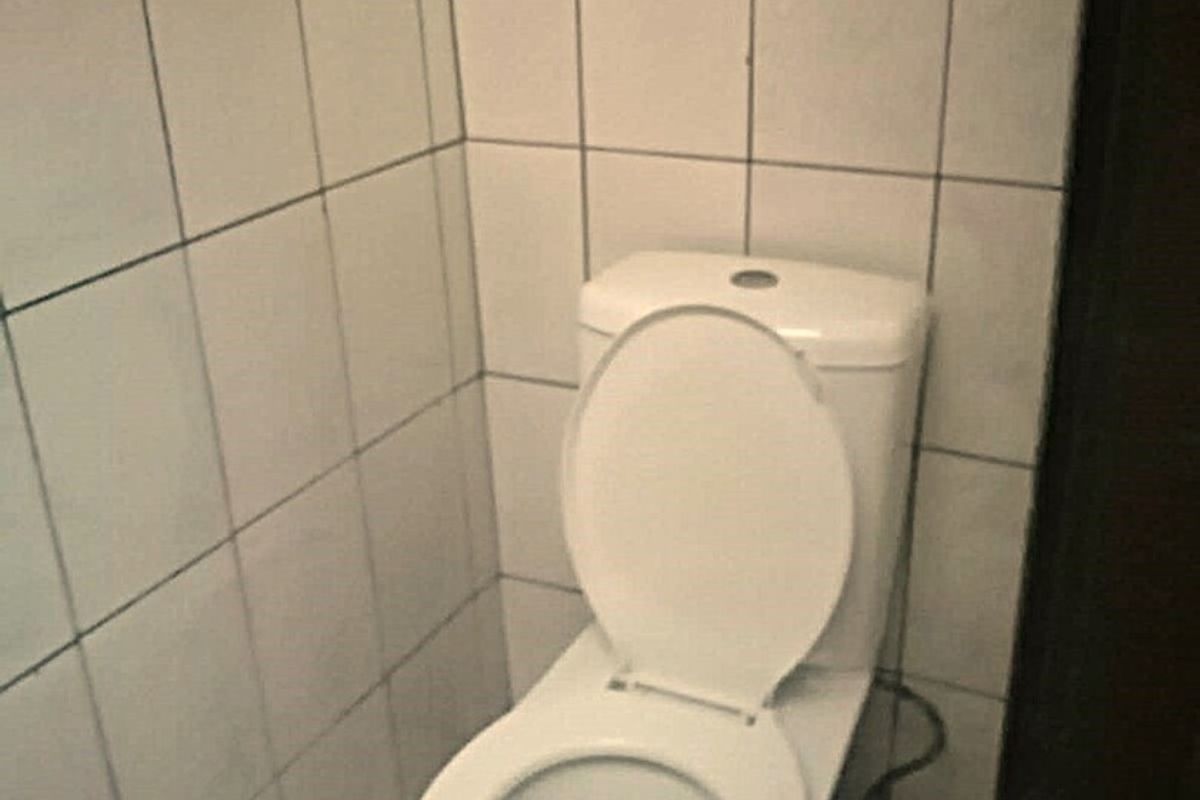 A small bathroom featuring a standard toilet with white ceramic wall and floor tiling.