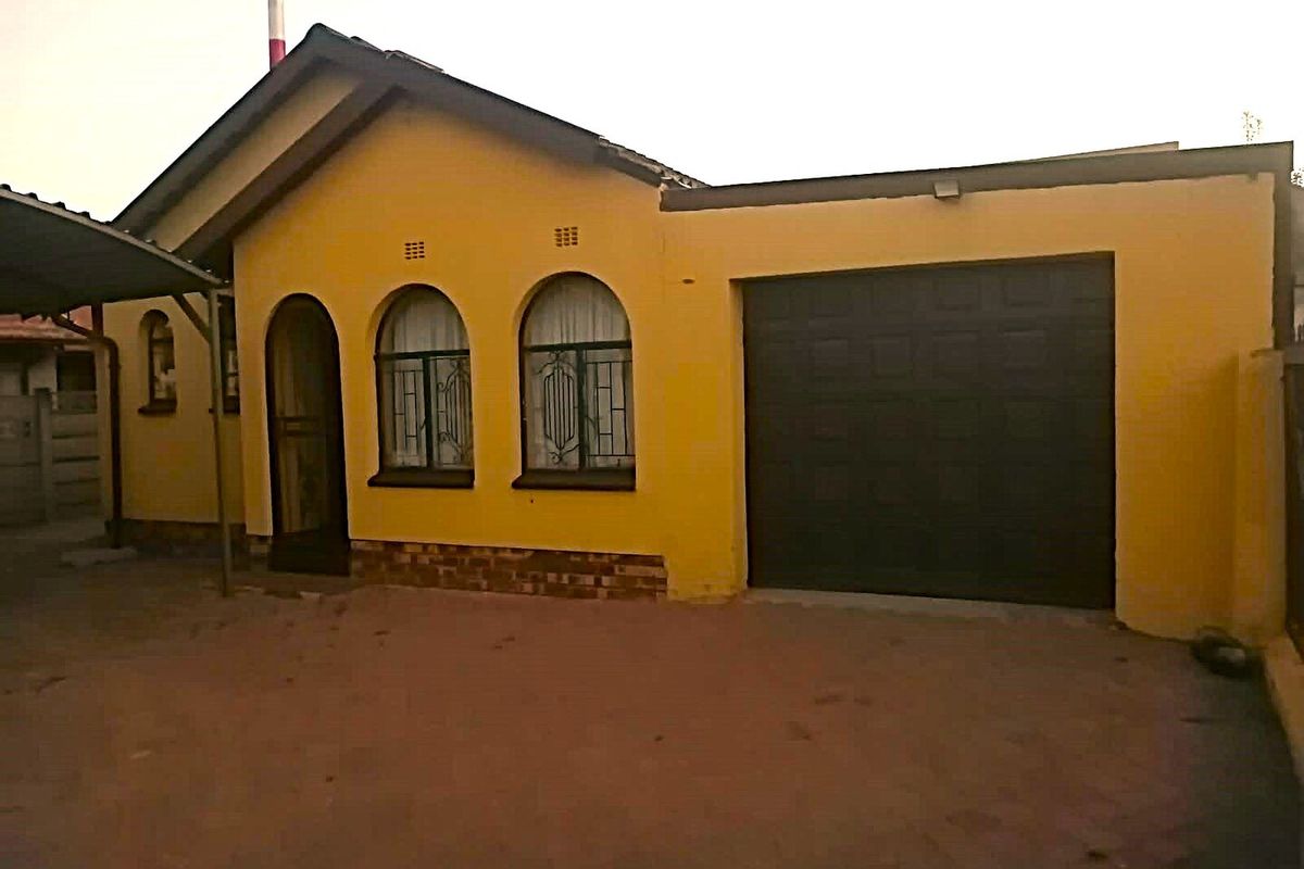 Front elevation of a single-story house featuring a garage, arched windows with security bars, and a paved driveway area.