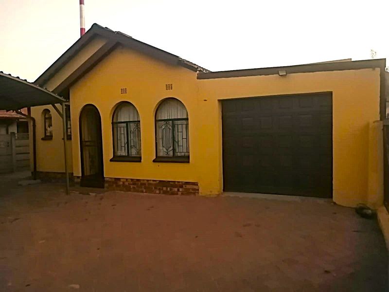 Front elevation of a single-story house featuring a garage, arched windows with security bars, and a paved driveway area.