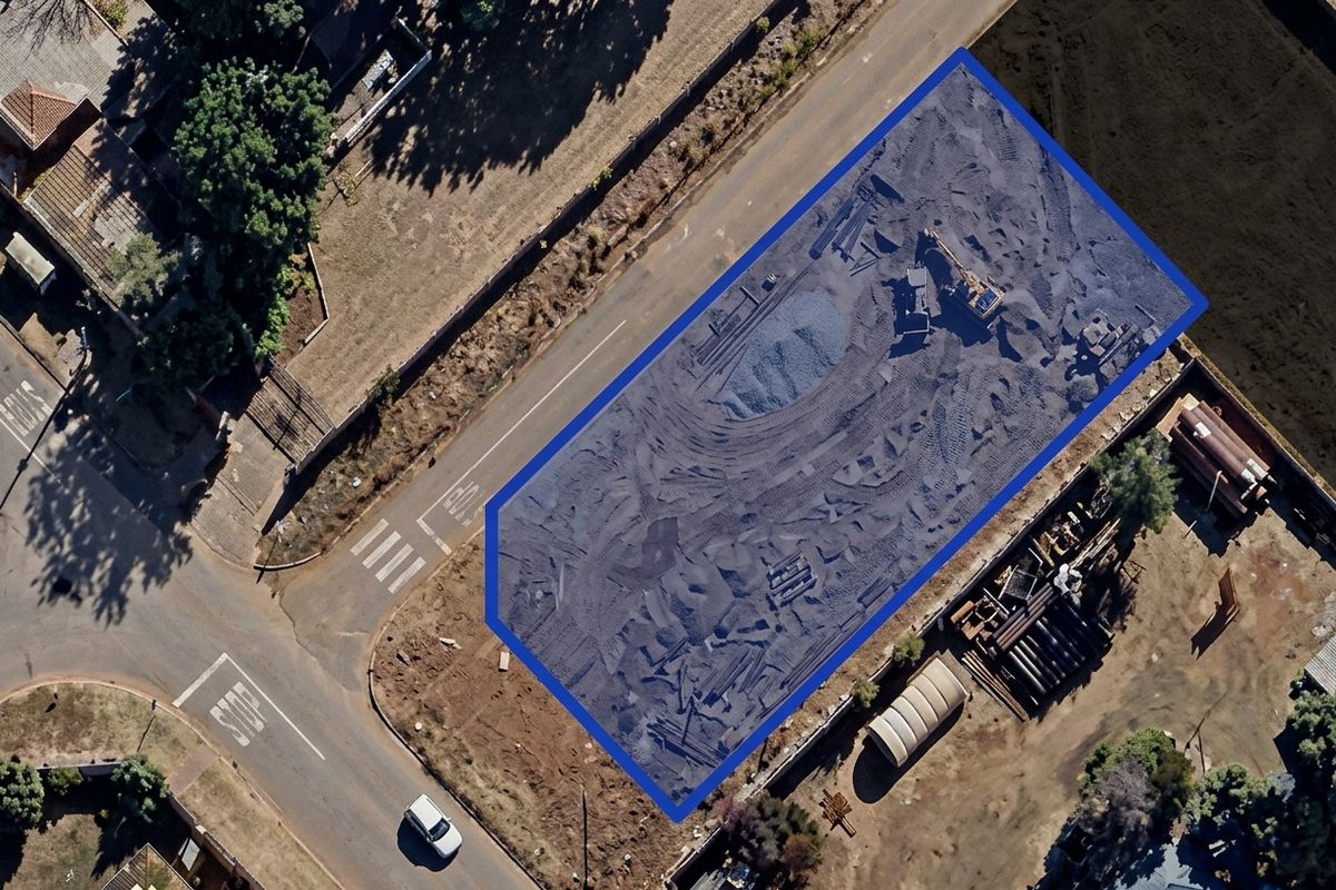 Aerial view of a vacant residential plot highlighted with a blue boundary, showing cleared land ready for development.