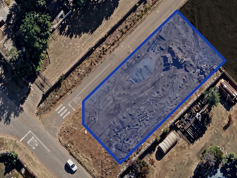 Aerial view of a vacant residential plot highlighted with a blue boundary, showing cleared land ready for development.