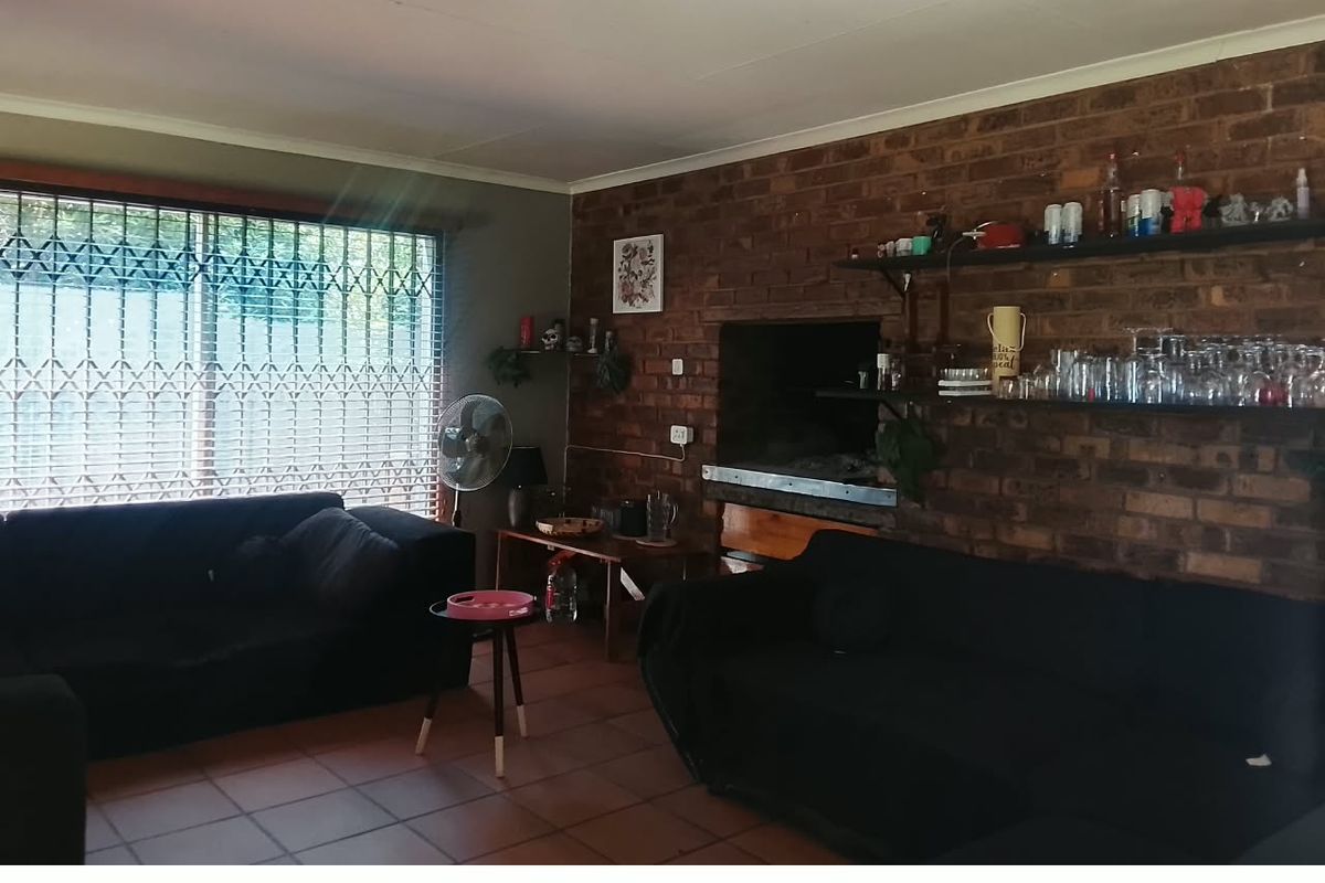 Living room featuring an exposed brick feature wall with a built-in fireplace, tiled flooring, and large windows secured with metal security gates.