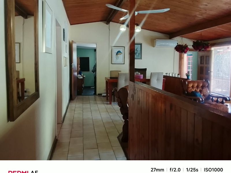 Living area featuring a timber-clad ceiling, tiled flooring, and a split-system air conditioner, with a timber partition wall separating the space.
