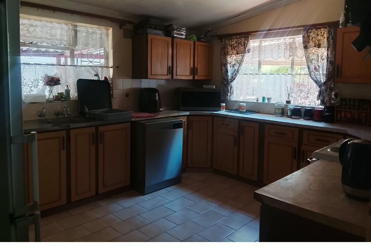 A dated kitchen featuring traditional laminate cabinetry, tiled flooring, and ample counter space, offering significant potential for a modern renovation.