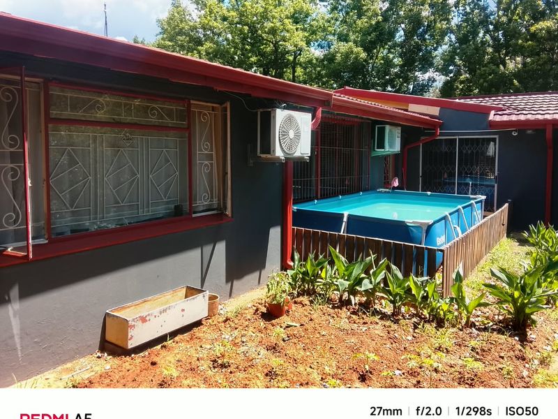 Rear exterior view of the house featuring a tiled roof, security bars on windows, and an installed air conditioning unit.