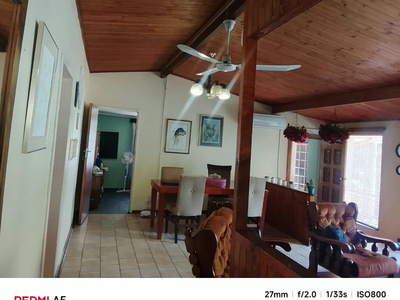 Open-plan living and dining area featuring a vaulted timber-clad ceiling, tiled flooring, and a split-system air conditioner.