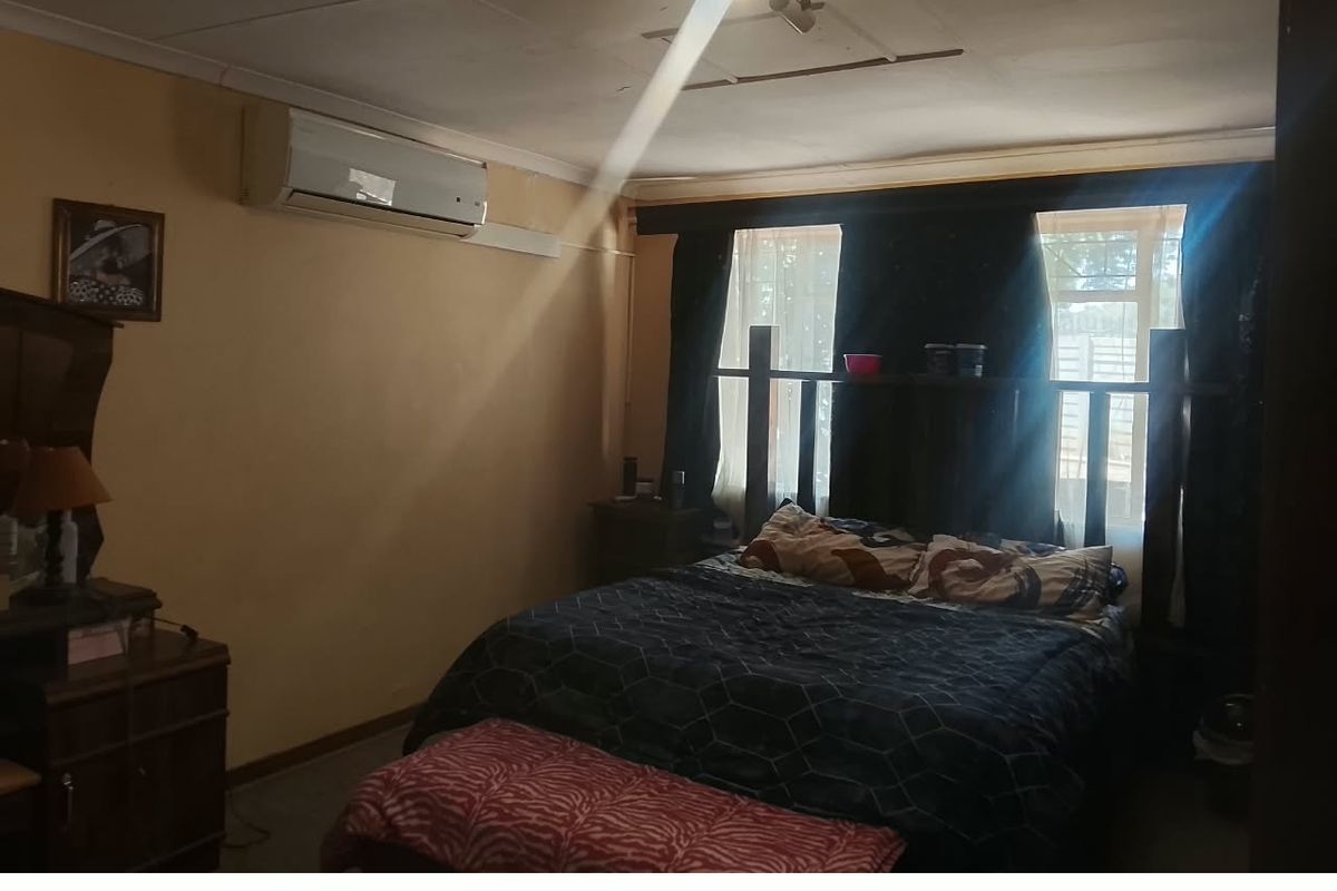 A bedroom featuring a wall-mounted air conditioning unit and a central ceiling light fixture.