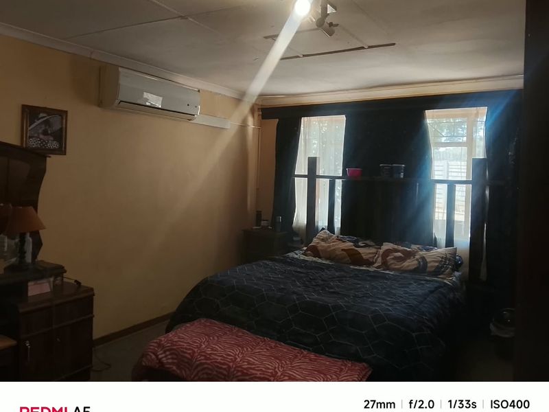 A bedroom featuring a wall-mounted air conditioning unit and a central ceiling light fixture.