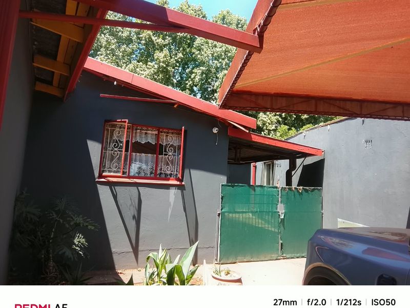 Rear exterior view of the property featuring a retractable awning, security gate, and security bars on the window.