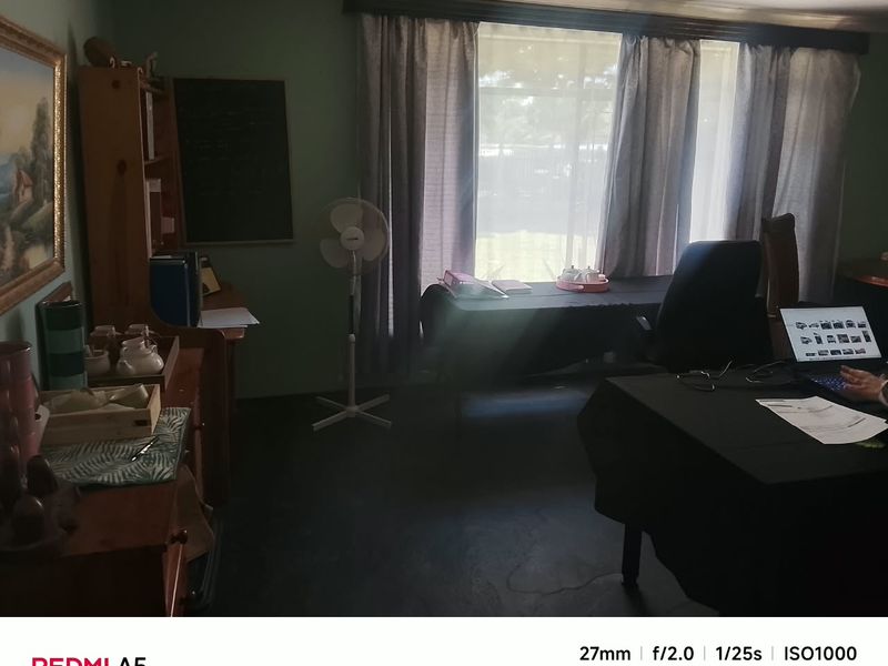 A functional home office space featuring large windows with curtains and decorative coving, providing a quiet area for work or study.