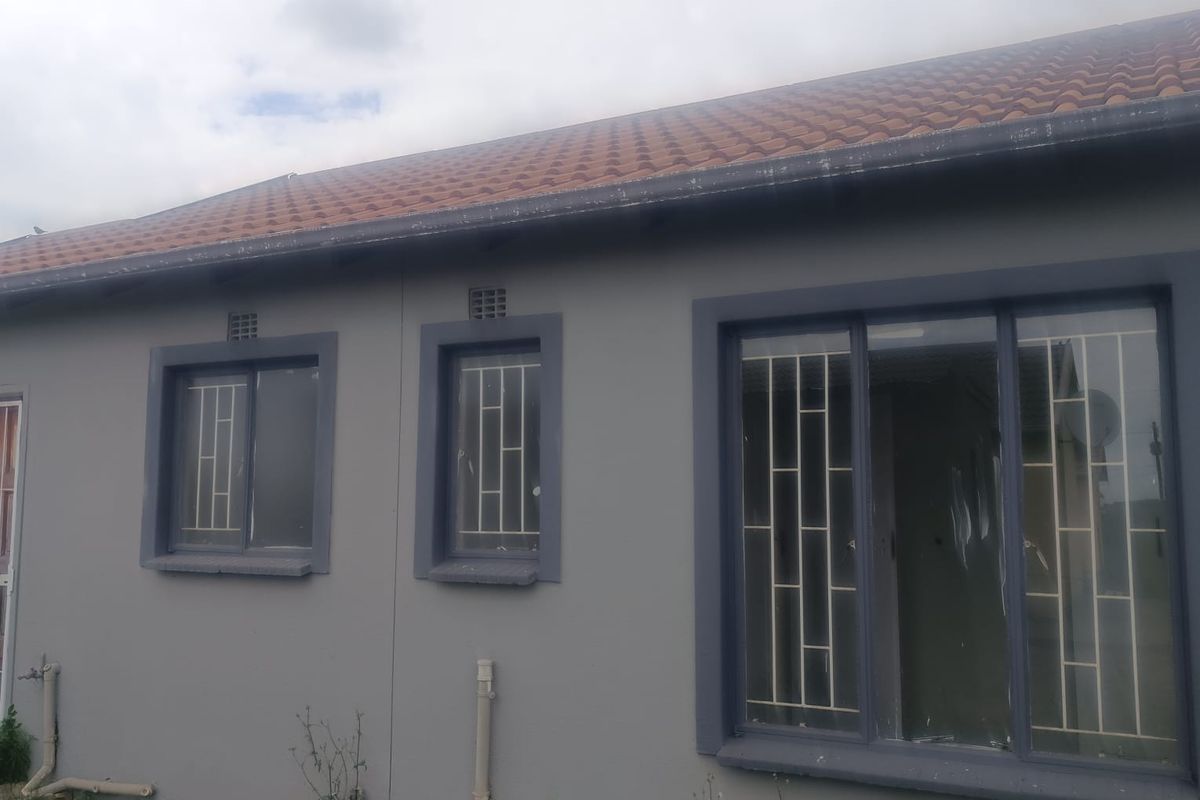 Rear exterior view of the house featuring terracotta roof tiles, security bars on windows, and external plumbing fixtures.