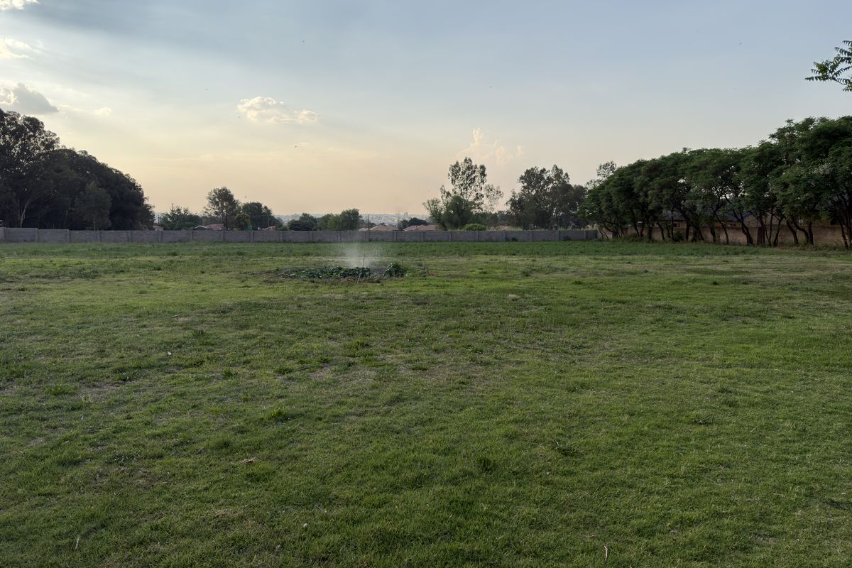 A spacious, level residential plot featuring a well-maintained lawn and a secure perimeter wall, offering potential for future development.