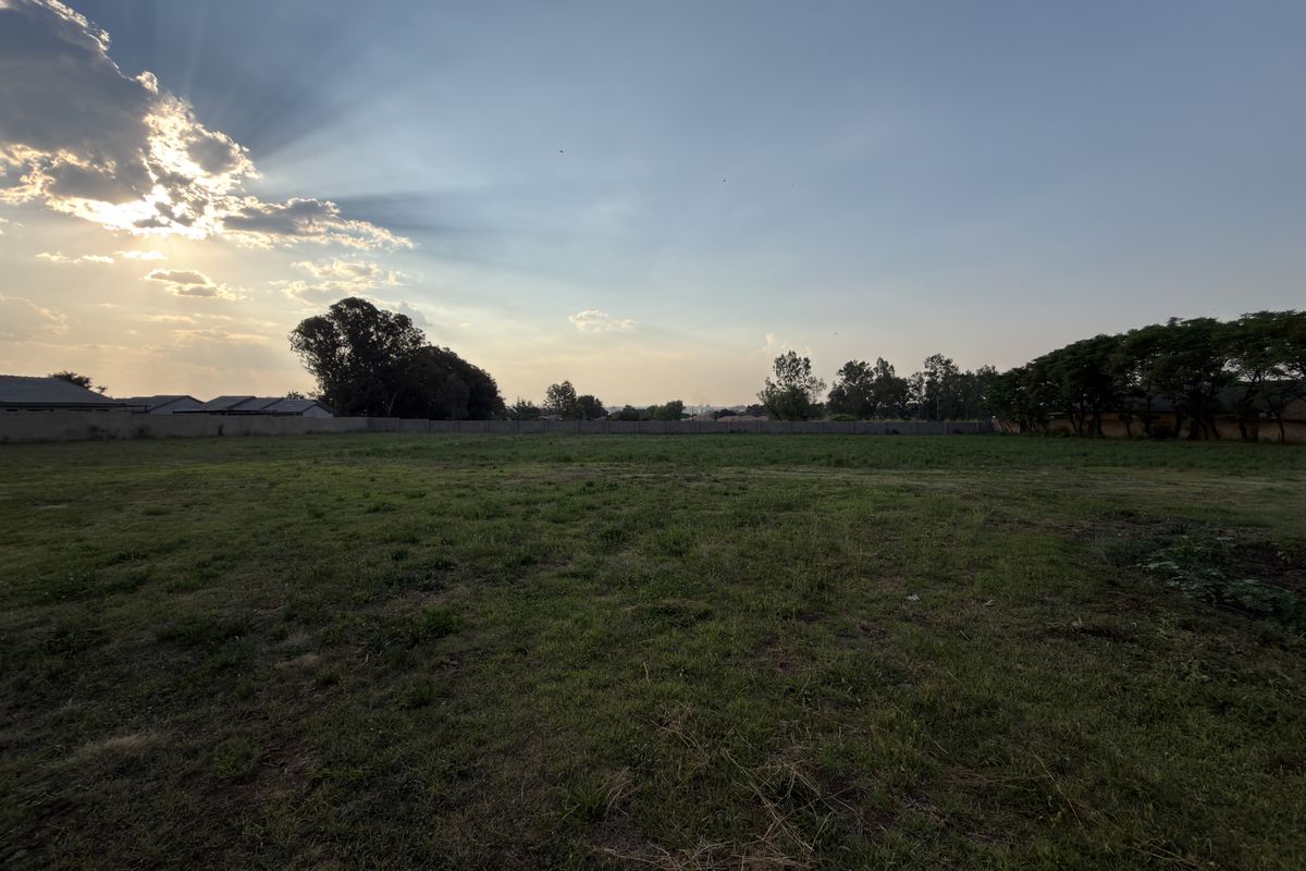A spacious, level residential vacant land plot featuring a grass lawn and perimeter walling, ideal for future development.