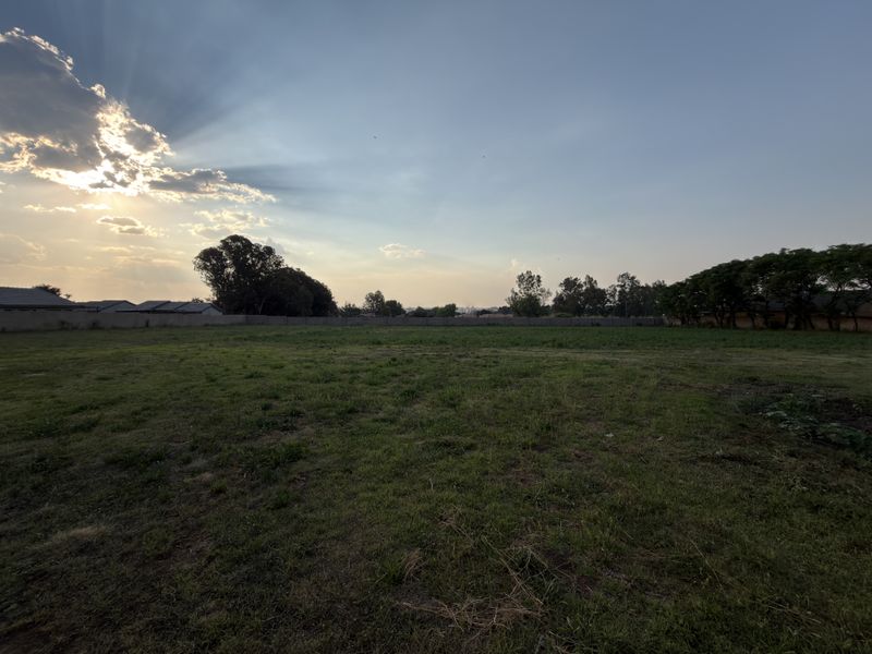 A spacious, level residential vacant land plot featuring a grass lawn and perimeter walling, ideal for future development.