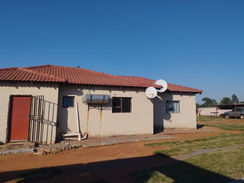 Rear view of the house featuring terracotta roof tiles, an external geyser, and security features including burglar bars and a security gate.