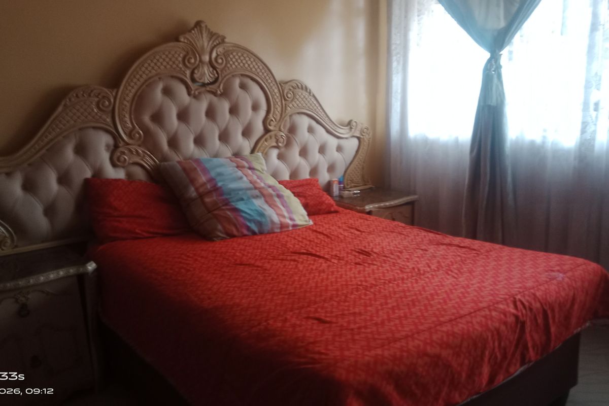 A bedroom featuring a large decorative headboard and window treatments.