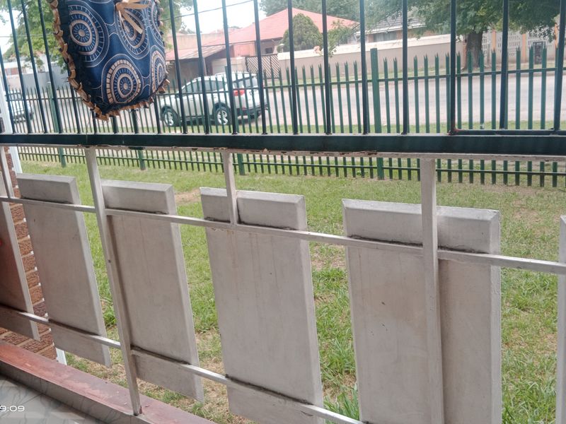 A covered patio area featuring metal security fencing and brick walling, showing signs of wear and requiring maintenance on the metal fixtures.