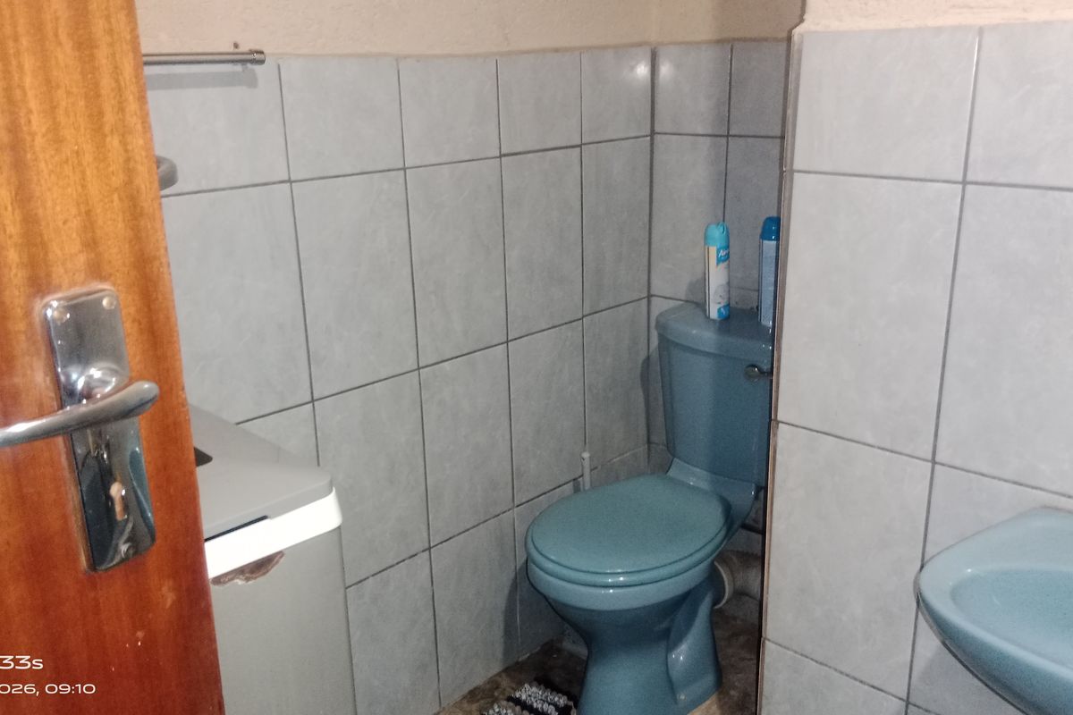 A compact bathroom featuring blue sanitaryware, tiled walls, and a wooden door, requiring cosmetic updates to improve its overall condition and appeal.