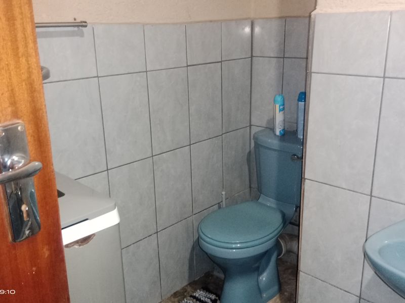 A compact bathroom featuring blue sanitaryware, tiled walls, and a wooden door, requiring cosmetic updates to improve its overall condition and appeal.