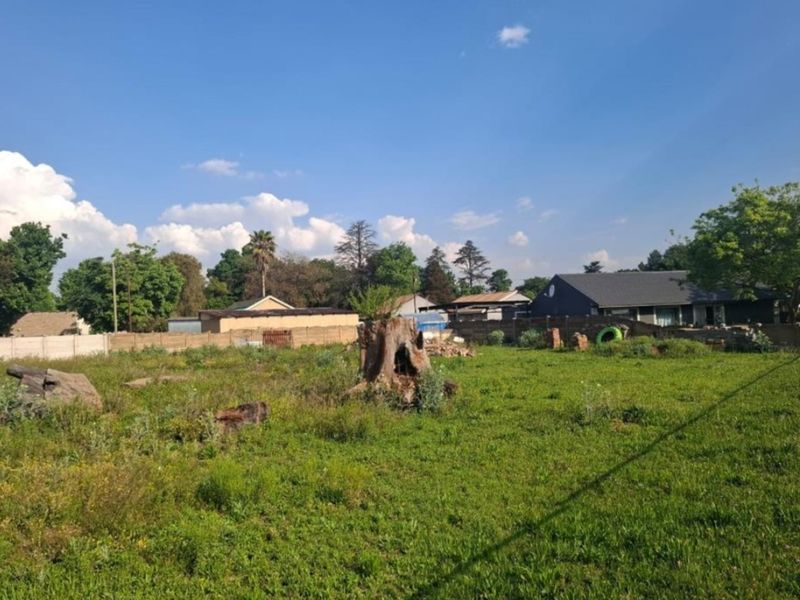 A vacant residential plot featuring a grass lawn and perimeter boundary walling, offering a blank canvas for future development.