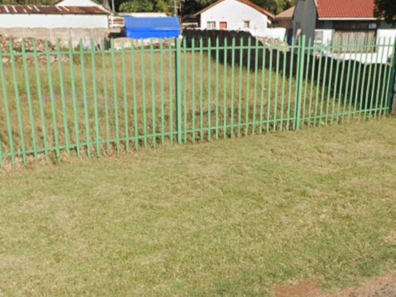 A view of the vacant residential land featuring green steel palisade fencing along the street boundary.