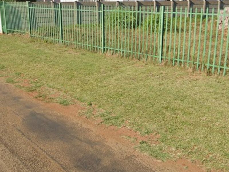 Street view of the property boundary featuring a metal palisade fence and adjacent paved road access.