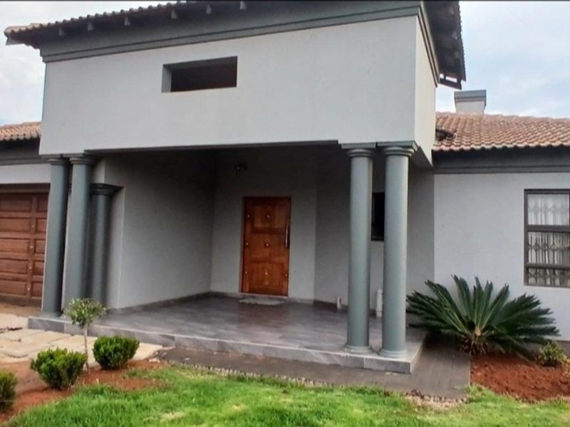 Front elevation of a modern house featuring a covered entrance porch with decorative columns, a wooden garage door, and tiled roof.