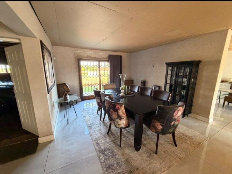 Dining room featuring tiled flooring and a sliding glass door with security gate, requiring ceiling and wall finish improvements.